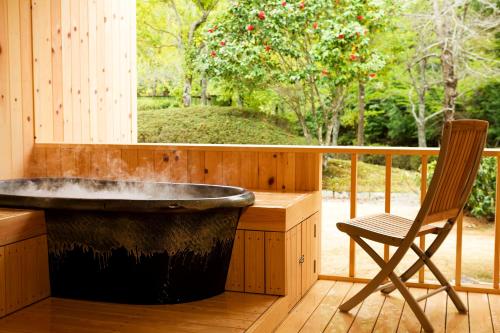 a bath tub sitting on a deck with a chair at Sennomori in Ise