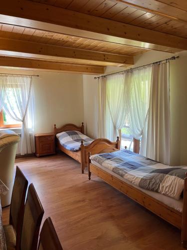 two beds in a room with wooden floors and windows at Chatka pod Dębami dla pracowników firm in Brzeźnica