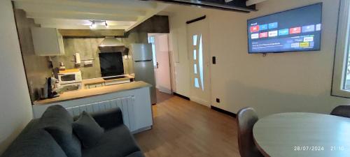 un salon avec une table et une télévision au mur dans l'établissement Le Cosy,Cabourg, à Cabourg