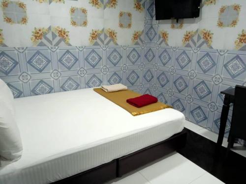 a small bedroom with a white bed with blue tiles at Kuala Selangor Hotel in Kuala Selangor
