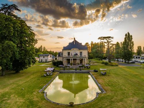a large house with a pond in front of it at Garrigae Manoir de Beauvoir Poitiers Sud - Hotel & Spa in Mignaloux-Beauvoir