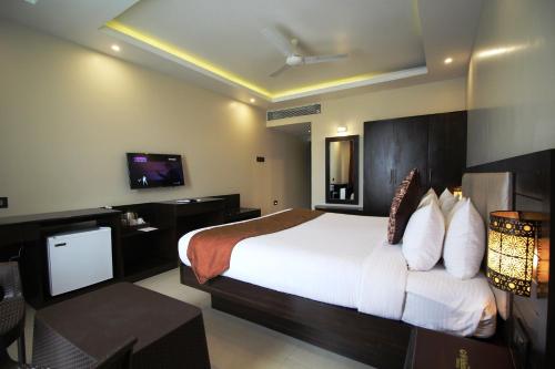 a hotel room with a bed and a television at Hotel Golden Plateau in Porvorim