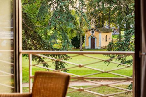 a window with a view of a church in a yard at Garrigae Manoir de Beauvoir Poitiers Sud - Hotel & Spa in Mignaloux-Beauvoir