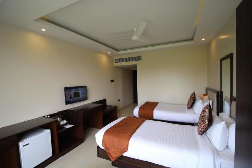 a hotel room with two beds and a television at Hotel Golden Plateau in Porvorim