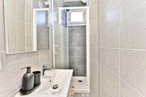 une salle de bain avec un lavabo blanc et un miroir dans l'établissement Séjour dans un 2 pièces confortable - Proche Paris, à Montreuil