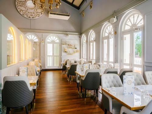 a dining room with tables and chairs and windows at The Sultan in Singapore