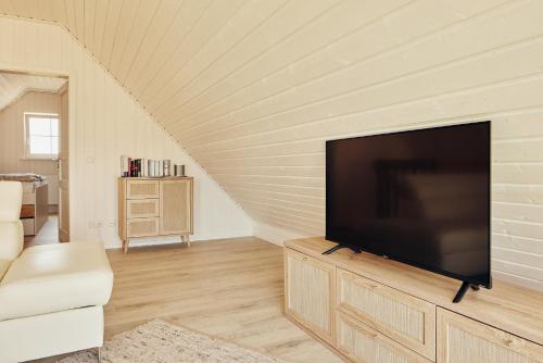 a living room with a flat screen tv on a wooden cabinet at Mein rotes Haus in Wandlitz