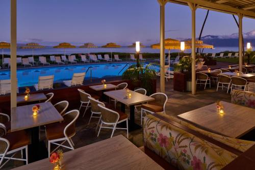 a restaurant with tables and chairs and a pool at Royal Lahaina Resort & Bungalows in Lahaina