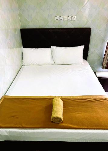 a bed with a brown blanket and white pillows at Bukit Beruntung Hotel in Rawang