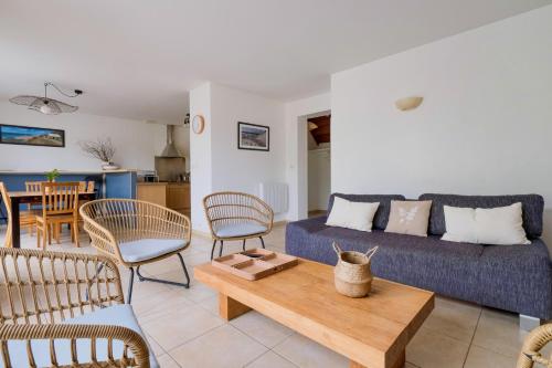 un salon avec un canapé bleu et des chaises dans l'établissement L'Oyat, à Barneville-Carteret