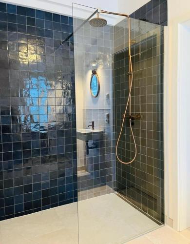a bathroom with a shower with blue tiles at Ferienhaus Slichtemolen in Saal