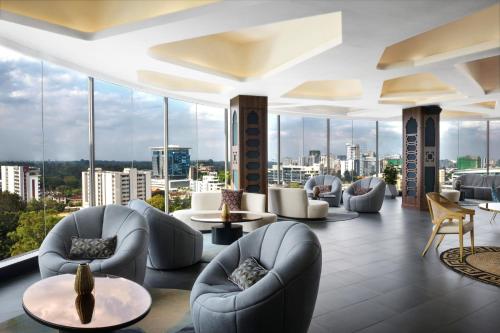 a hotel lobby with chairs and tables and windows at Novotel Nairobi Westlands in Nairobi