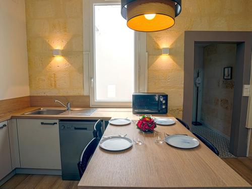 d'une cuisine avec une table avec des assiettes et des fleurs. dans l'établissement Le Repos Urbain au coeur de Libourne, à Libourne