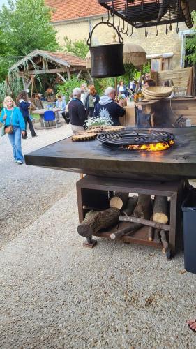 a picnic table with a grill and people standing around at La Grange en Champagne in Hermonville