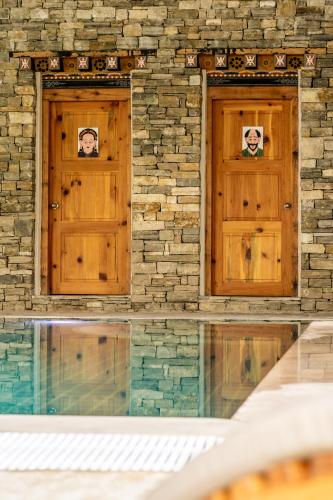 two wooden doors in a stone building with a pool at Zhiwaling Heritage in Paro