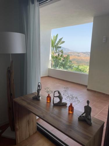 een houten tafel met drie beelden erop met een raam bij Your dream is real in La Cala de Mijas