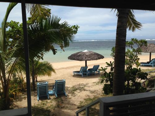two chairs and an umbrella on a beach at Savaii Lagoon Resort in Fagamalo
