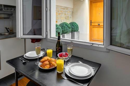 - une table avec des assiettes de nourriture et une bouteille de vin dans l'établissement Bluestay 205 - Charmant Studio à Paris, à Paris