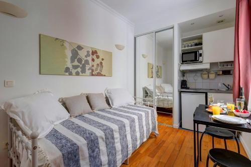Cette petite chambre comprend un lit et une cuisine. dans l'établissement Bluestay 205 - Charmant Studio à Paris, à Paris