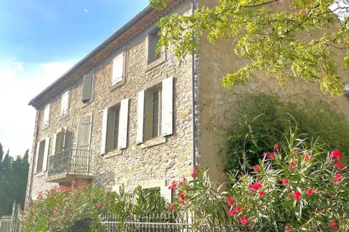 a brick building with flowers in front of it at Maison vigneronne de Bonne Maman - climatisée in Cesseras