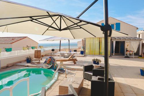 un patio avec un parasol et une piscine dans l'établissement Spacieuse et chaleureuse villa vue mer Marseille, à Marseille