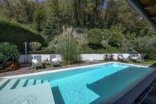 a swimming pool in a garden with chairs and a table at Villa Rondine - Villa mit beheiztem Pool in Salò
