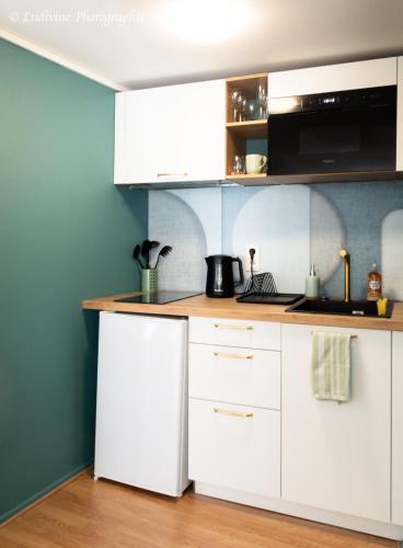 une cuisine avec des armoires blanches et un réfrigérateur blanc dans l'établissement Cozy aux 3 frontières, à Sierck-les-Bains