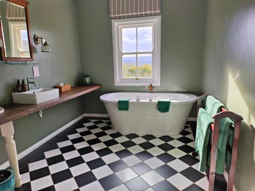 a bathroom with a tub and a checkered floor at Camp Figtree by The Oyster Collection in Addo