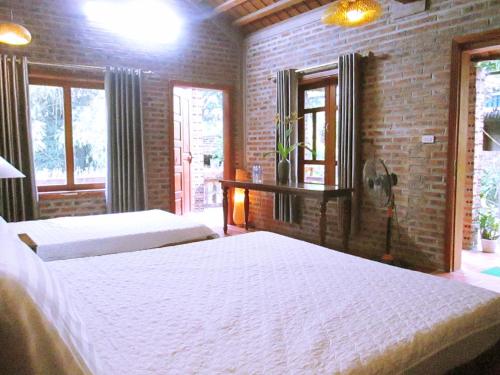 a bedroom with two beds and a brick wall at Ninh Binh Nature Homestay in Ninh Binh