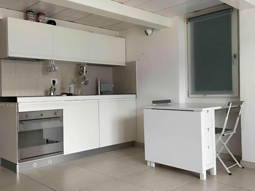 a kitchen with white cabinets and a table in it at Casa PG - Appartamento Vista Lago in Monte Isola