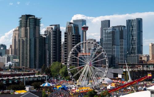 a ferris wheel in front of a large city at Cozy 2BR Condo with King Bed and City Views in Calgary