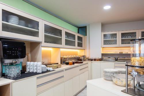 una cocina con armarios blancos y platos en la encimera en Steris Elegant Beach Hotel, en Rethymno