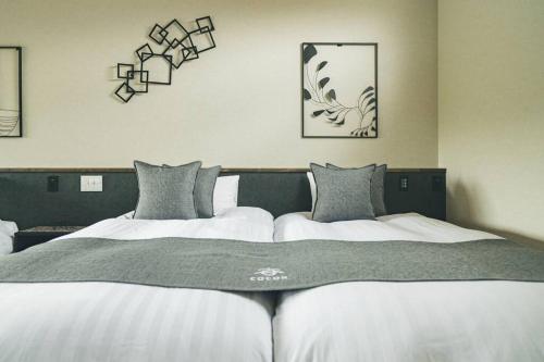a large bed with white sheets and gray pillows at Cocon富士 in Fujikawaguchiko