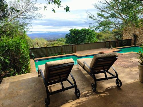 two chairs and a table next to a swimming pool at Camp Figtree by The Oyster Collection in Addo
