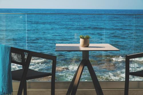 a table and chairs in front of a window with the ocean at Elia Sea Suites in Chania Town
