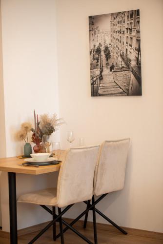 a dining room table with chairs and a picture on the wall at Emerald Residence Apartments in Dunajská Streda