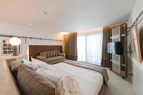 a bedroom with a large bed and a couch at Folie Marine Hotel & Beach Club in Jal