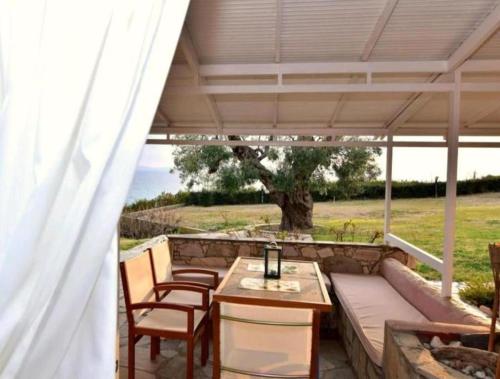 a patio with a table and chairs under a roof at Aegean View Maisonnette in Neos Marmaras