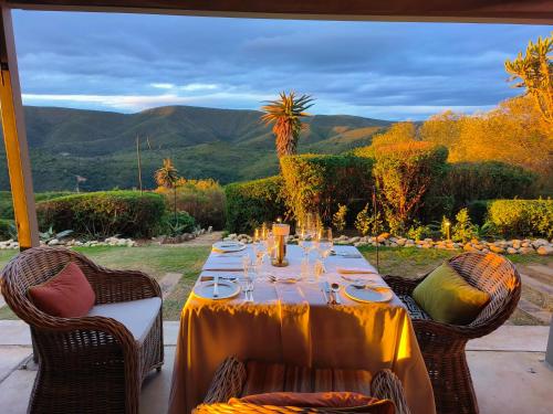 a table with plates and wine glasses on a patio at Camp Figtree by The Oyster Collection in Addo