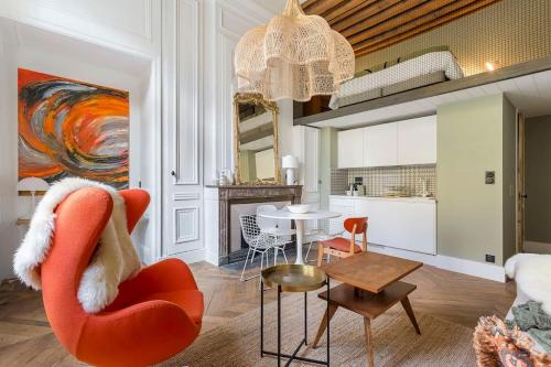 un salon avec une chaise rouge et une table dans l'établissement L'Eugénie, secteur Opéra et climatisé, Lyon 1er, à Lyon