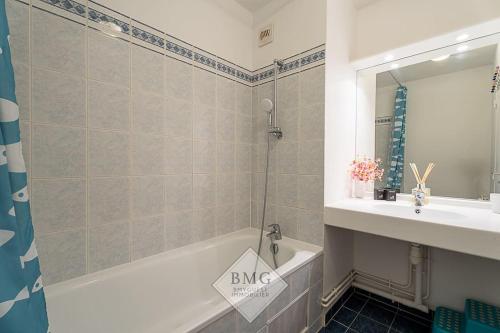 une salle de bain avec une baignoire et un lavabo et une baignoire dans l'établissement Danube appartement Disneyland, à Serris