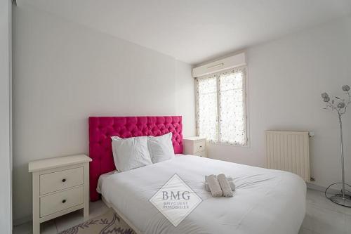- une chambre blanche avec un grand lit et une tête de lit rose dans l'établissement Danube appartement Disneyland, à Serris