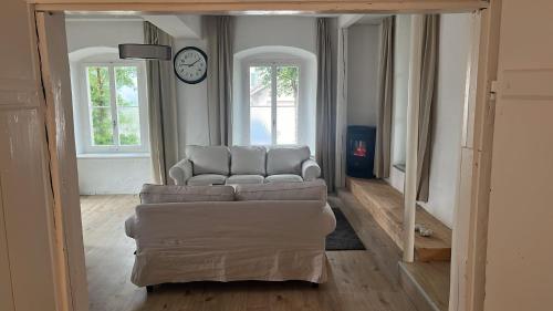 a living room with a couch and a clock on the wall at Loftfeeling in Hombrechtikon