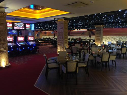 a dining room with tables and chairs and slot machines at Casino & Hotel Admiral Strážný in Strážný