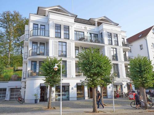 a white building with people walking in front of it at Villa Paula in Sellin - WG01 "Findling" strandnah mit Kamin, Terrasse, Balkon in Ostseebad Sellin