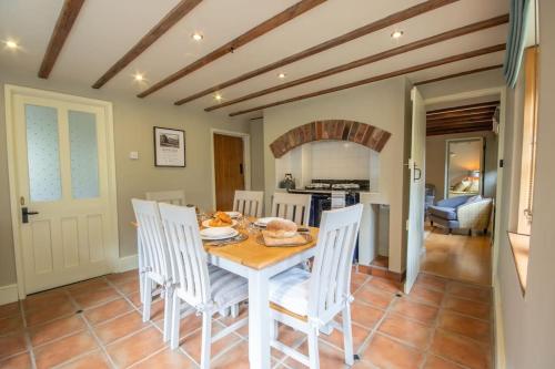 ein Esszimmer mit einem Tisch und weißen Stühlen in der Unterkunft Riverside Cottage Alstonefield Peak District in Alstonfield