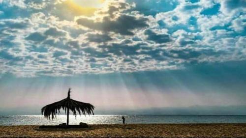a umbrella on the beach with a rainbow in the sky at Aqua Sun in Nuweiba