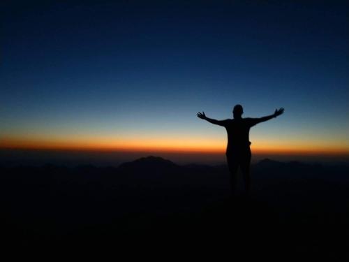 a man standing on top of a mountain with his arms outstretched at Aqua Sun in Nuweiba
