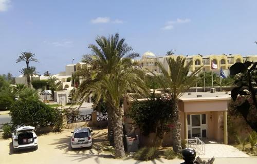 a parking lot with palm trees in front of a building at Appartement Lella Mariam Zarzis in Zarzis