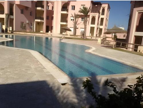 a swimming pool in front of a building at Appartement Lella Mariam Zarzis in Zarzis